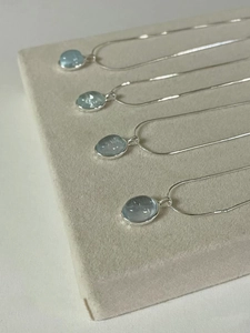 Macro view of oval light blue gemstone pendants on silver chains in parallel display
