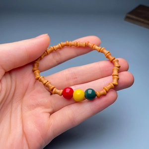Detail of wooden bamboo-shaped bead bracelet with colorful accent beads held in hand