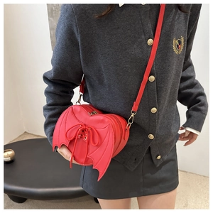 Detail of red bat wing crossbody bag with corset lace design on dark grey knitwear