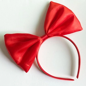 Detailed view of the red satin fabric texture and bow fold on this girl's headband