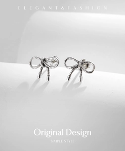 Detailed shot of S925 silver bow stud earrings with vintage woven texture finish