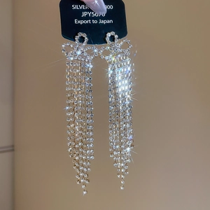 Detailed macro of long silver tassel earrings with glittering rhinestones and bow design