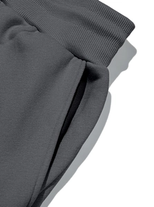 Detail of deep gray jogger pants showing ribbed waistband and reinforced side pocket stitching