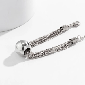 Macro detail of silver layered metal chain necklace with large round bead pendant