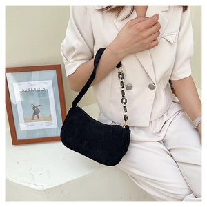 Detail of black corduroy shoulder bag with textured fabric and acrylic chain strap