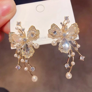 Detailed view of butterfly earrings with crystal zircons and hanging white pearls