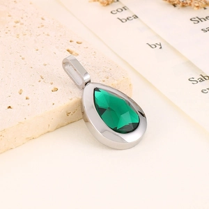Detailed view of water drop green diamond pendant on a textured stone display
