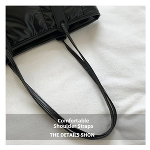 Detail showing the comfortable slim black shoulder straps of the quilted down tote bag