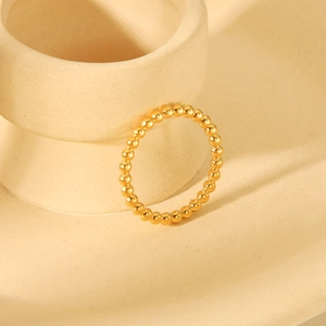 Macro shot of gold beaded titanium steel ring on a minimalist ceramic display