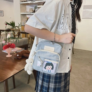 Gros plan du mini sac bandoulière en nylon bleu clair avec ours et écussons