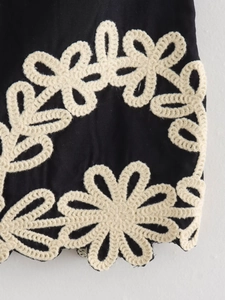 Vue macro détaillée de broderies florales au crochet beige sur tissu en coton noir
