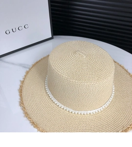 Detail shot of the woven straw hat with elegant white pearl trim and frayed brim edge