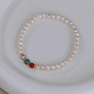 Detail of freshwater pearl bracelet with colorful agate beads and gold spacers on ceramic