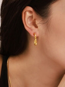 Close-up of golden bamboo shaped hoop earring on model showing texture and fit