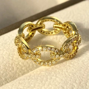 Detail macro of a gold Cuban link chain ring with micro-pave zirconia in a jewelry box