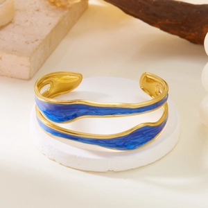 Detailed shot of gold-plated wavy bangle with deep blue enamel inlay and open-ended design