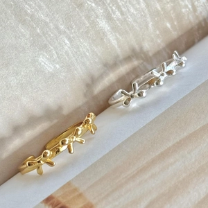 Minimalist S925 silver bow rings in gold and silver finish on a textured background