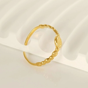 Bague ajustable en acier doré avec motifs floraux gaufrés sur un support blanc élégant