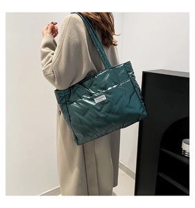 Close-up of dark green quilted tote bag with fashion label and glossy puffer texture