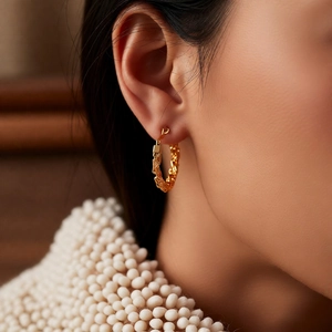 Macro detail of 24k gold plated twisted hoop earrings with woven texture on a model