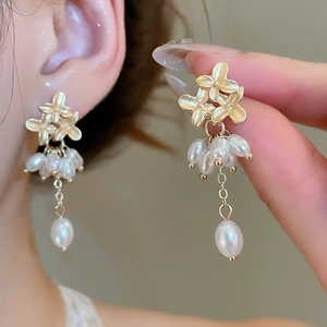 Macro detail of golden flower earrings with hanging pearls and delicate tassels