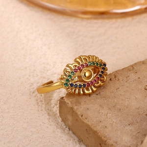 Macro detail of gold Evil Eye ring with colorful zircon stones on natural stone base