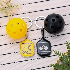 Detail view of yellow and black pickleball paddle keychains with mini sports balls