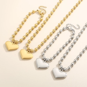 Set of four gold and silver beaded titanium steel bracelets with heart shaped pendants