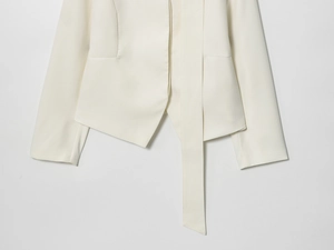 Dettaglio blazer crema con cintura decorativa coordinata e trama del tessuto sull'orlo