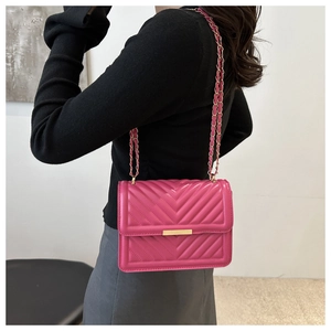 Pink quilted leather crossbody bag with gold chain strap shown on a model