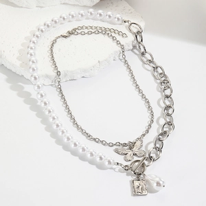 Detail of layered baroque pearl necklace with butterfly pendant on stone background
