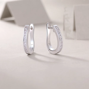 Close-up of silver U-shaped hoop earrings featuring a double row of sparkling moissanite