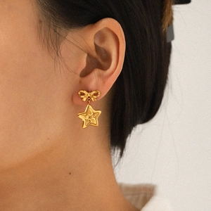Elegant 18k gold stainless steel bow and star drop earrings worn on model for a luxury look