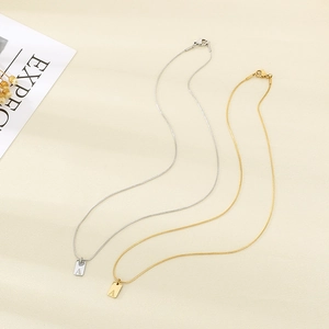 Detail van de 18K vergulde rechthoekige letter A-hanger aan een roestvrijstalen slangenketting