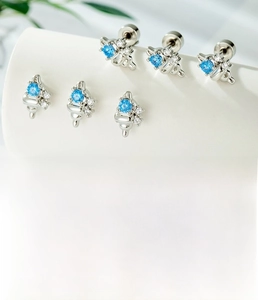 Detailed view of silver seashell ear stud with blue zircon on white display stand