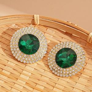 Macro shot of vintage round gold earrings with a green gemstone and crystal accents