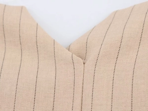 Gros plan du décolleté en V sur tissu kaki rayé montrant les détails de la texture