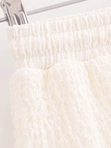 Detailed macro view of white pleated fabric texture and elastic waistband on metal hanger