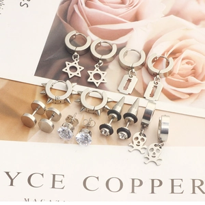 Detailed set of silver stainless steel earrings with star and skull charms on floral background