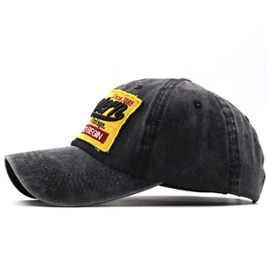 Dettaglio del cappello in cotone lavato con patch vintage ricamata su tessuto antracite