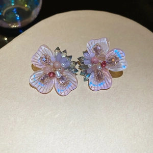 Macro detail of crystal flower earrings with purple petals and small pearl accents