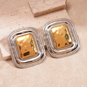Macro shot of two-tone square geometric earrings with hammered silver and gold textures