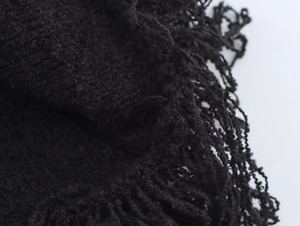 Dettaglio della trama in maglia nera e delle eleganti frange sull'orlo della gonna