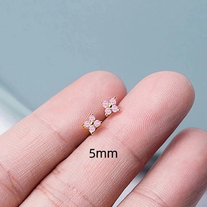 Macro shot of a 5mm mini four-petal flower earring with pink zircon on a finger tip