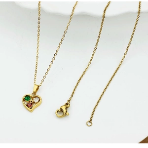 Detail of a gold heart pendant necklace featuring inlaid red, green, and white gemstones