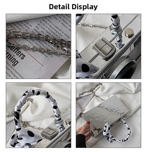 Close-up details of silver camera-shaped bag with polka dot ribbon and chain strap