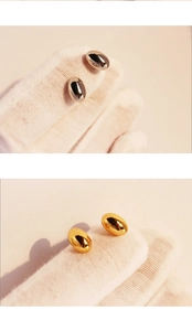 Macro shot of minimalist bean-shaped stud earrings in polished gold and silver finishes