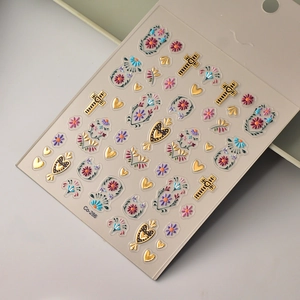 Detail of 3D embossed nail stickers featuring gold crosses, hearts and colorful floral patterns