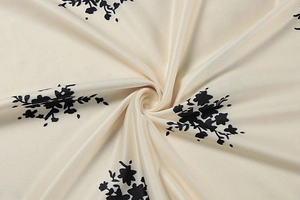 Detailed view of cream fabric featuring black floral patterns and soft draped texture