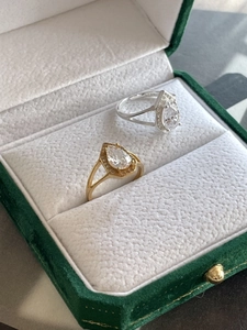 Detail view of pear-shaped rings with hexagonal halo and S925 stamp in green velvet box